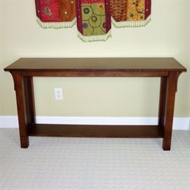 Mission Style Console Table: A Mission style console table with a dark walnut stain. It has four flat slats at the sides and lower shelf.