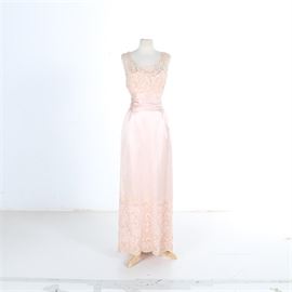 Silk Chantilly Lace French Satin and Lace Evening Dress: A Silk Chantilly Lace French satin and lace evening dress. This satin floor length piece features an illusion neckline with an overlay of pink lace. The bodice meets a fitted wide waist and the lace accents the bottom of the skirt. A pleated satin panel train completes the design.