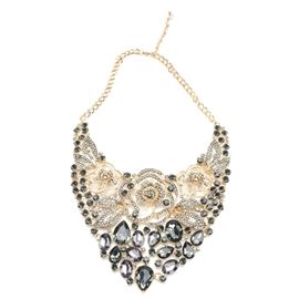 Gold Tone Statement Necklace With Rhinestones: A gold tone statement necklace with rhinestones. This gold tone bib necklace features open work floral detailing, clear and smoky grey rhinestones, and lobster claw clasp. There are no visible hallmarks on this necklace.