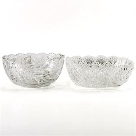 Crystal Bowls: A selection of two crystal bowl. This selection includes a round bowl with a jagged cut scalloped edge and a cut floral and foliate pattern around the body. Also in this selection is a square bowl with a scalloped edge and a cut wheat and diamond design around the body. These items are unmarked.