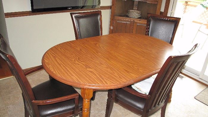 Oak dining table with four leather upholstered chairs.