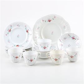 Floral Ceramic Tableware: A set of floral ceramic tableware. This set includes a total of eighteen pieces, consisting of dinner plates, saucers, teacups, and a large serving dish. The matching set shows a white ceramic surface with floral motifs accented throughout the border and center.