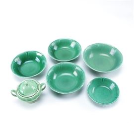 Set of Green Glazed Ceramic Dishes: A collection of vintage green glazed ceramic dishes. Included in the set are one lidded sugar bowl, one large bowl, three medium size bowls, and one small bowl. All pieces feature a matching embossed petal motif along the inner rim.