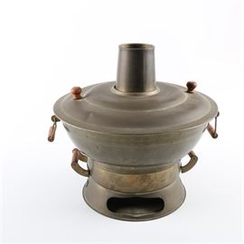 Brass Hibachi Brazier: A brass hibachi brazier. This cooking tool includes a base with a perforated surface for burning charcoal, a cooking basin with a tubular central chimney, a brass lid, and six woven wire scoops.