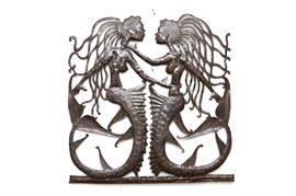 John Sylvestre Metal Folk Art Wall Sculpture: A one of a kind Folk Art wall sculpture comprised of recycled steel drums by the Haitian artist, John Sylvestre who is best known for his hand crafted metal sculptures. This wall sculpture features two mermaids with long snake-like hair, which is signed by the artist along one of the arms. There is a hook for hanging to the verso.