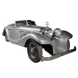 Custom Made Miniature Mercedes Benz Roadster Car: A custom made miniature Mercedes Benz Roadster. This car features a silver fiberglass exterior, cream leather seat, wooden dashboard, four Michelin tires, a Momo road wheel, a Fitchel & Sachs motor, and a 47cu cm engine. The vehicle is labeled “Mercedes Benz” on the grill and all four hubcaps. The engine is located in the trunk of the car and is marked “Fitchel & Sachs AG Schweinfurt Mot. No. 11100323 Hub. R 47 TYP Sachs 50/ADLX”.