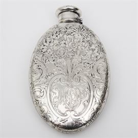 Antique Tiffany & Co. Sterling Silver Flask: An antique Tiffany & Co. sterling silver flask. This flask is oval in shape with an elaborately decorated floral and foliate design on the front and part of the back. This design frames a discretely placed monogram. The lid is decorated in a matching design and is a hinged screw top. The flask is marked to the underside “Tiffany & Co. 4705 Makers 6561 Sterling Silver 925-1000 1 Gill”. The total approximate weight, inclusive of all materials, is 4.530 ozt.