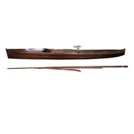 Vintage Mahogany Sailing Canoe: A vintage mahogany sailing canoe. This canoe features an elongated body made of mahogany planks bolted together. It comes with a mast, boom, and single oar. A label attached reads “Sailing Canoe in Mahogany Circa 1930 — made in Ohio Has mast, boom, and keel”.