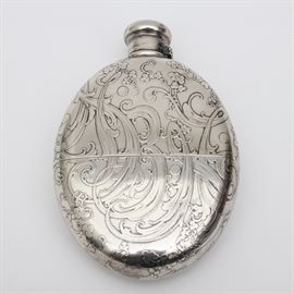 Tiffany & Co. Sterling Silver Flask with Removable Cup: A Tiffany & Co. sterling silver monogrammed flask. This flask has an oval shaped body and a screw top, hinged lid. The front of the flask is decorated with a scrolling floral and foliate design with the initials “HBK” sprawled across the front in a matching design. The bottom half of the flask removes to serve as a cup for the flask. Under the cup, the bottom of the flask is marked “Tiffany & Co. 2811M 26 Sterling 2 Gill”. The total approximate weight, inclusive of all materials, is 9.485 ozt.