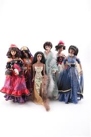 Collectible Dolls: A collection of six dolls. This group includes dolls that represent adult females in various outfits including evening gowns, a 1920s flapper style, a flamenco dancer and more. The doll in the black red and white off the shoulder gown is marked to the neck “AEL A474”.