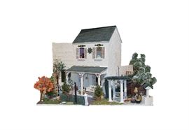 Handmade Doll House: A handmade doll house. This doll house features a wooden construction with a hand molded white plaster material, green roof, and pink and green details. The house is decorated by trees, patio furniture, interior furniture, and more.
