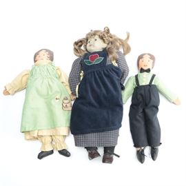 Vintage Composite and Cloth Dolls: A selection of three vintage composite and cloth dolls. The largest has a composite head with glass eyes and rooted hair on a cloth body with a blue and white dress. The other two are entirely cloth bodied with cream and green clothing decorated with bee motifs.
