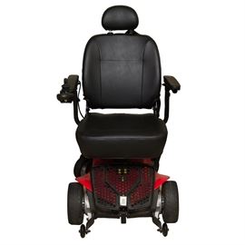 Pride Jazzy Elite ES Motorized Wheelchair: A Pride Jazzy Elite ES motorized wheelchair. It features a cushioned folding backrest and seat, an adjustable headrest, and a folding arm with a toggle control panel. The seat rests on a motorized base with nine-inch rubber drive wheels, six-inch rear-mounted rubber caster wheels, and three-inch front-mounted plastic anti-tip wheels. It stops with the aid of electronic regenerative brakes, with a disc parking brake. The chair has a two motor, front-wheel drive train powered by two rechargeable twelve-volt U-1 batteries. It has a maximum speed of 4 mph and a range of up to 15 miles. Weight capacity is 300 lbs. Includes a Pride Mobility Products ELECHG1024 charging cord. Untested.