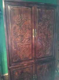 finely carved relief, interior upper fitted with shelving, lower with drawers