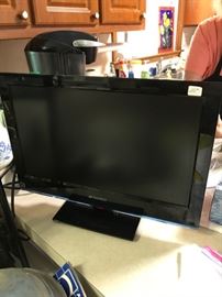 One of two flat screen TVs in the sale, plus several television stands.