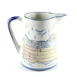 Noah's Ark Themed Louisville Stoneware Pitcher: A Noah’s Ark themed pitcher produced by Louisville Stoneware. This pitcher has straight tapered sides and an angular spout. It has been painted with an illustration of Noah’s Ark filled with animals, and the quote “And the rain was upon the earth forty days and forty nights” on the side. It is marked to the underside “Louisville Stoneware”.