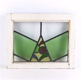 Vintage Wooden Window Frame With Stained Glass: A vintage wooden window frame with stained glass. The glass was made with a pebbled surface and features geometric shapes with a stylized center portion depicting foliage. The frame is wooden and painted white.