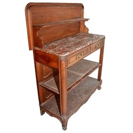 Antique Provincial Louis XV Style Metamorphic Marble Top Buffet: An antique Provincial Louis XV style metamorphic marble top buffet. This piece has a walnut finish. It features a rectangular wooden top with rounded corners that his hinged, and when raised it becomes a vertical gallery with a shelf. It reveals a rose hued marble work surface. Below the top is a square apron with a row of two dovetail jointed drawers, with brass-toned flourish shaped pulls. The piece has two rounded legs at the front corners above carved cabriole style feet, with a caned shelf and a low wooden shelf. It has a recessed back panel and square back feet.