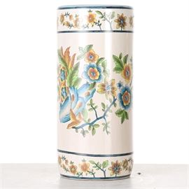 Lisa Aurel Porcelain Umbrella Stand: A Lisa Aurel porcelain umbrella stand. This piece is off white in color and is accented with a blue, orange, yellow, and green floral design at extends around the middle of the stand. It is accented by a smaller, similar design framed in dark blue around the rim and base. The umbrella stand is stamped to the underside “Porcelaine Peitea la Main Fait en Chine Pour Lisa Aurel.