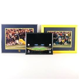 Michigan Wolverines and Ohio State Buckeyes Framed Photograph: A mixed lot of college football framed photographs. Lot includes; a 2011 photograph of Michigan Stadium – Under The Lights – at the Big House, presented behind glass in a black composite frame. A framed photograph of Ohio State David Boston (9) victorious and taunting Michigan Charles Woodson (2) after making a touchdown catch, November 22, 1997, presented behind a yellow and gray mat in a yellow composite frame. The third photograph presented behind navy and yellow mat depicts Michigan State player Desmond Howard against Notre Dame, titled The Catch, dated to plate “October 19, 1991.”