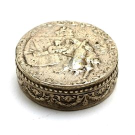 Fratelli Coppini 800 Silver Pill Box: A hinged pill box made of 0.800 silver by Fratelli Coppini of Italy. This piece has an embossed design to lid of a musician playing the cello or bass, with raised beading and swag elements along sides. It is marked “Made in Italy, Flli Coppini, 800” with manufacturer’s pictograph, a stamp that was in use until approximately 1933. The total approximate weight is 0.680 ozt.