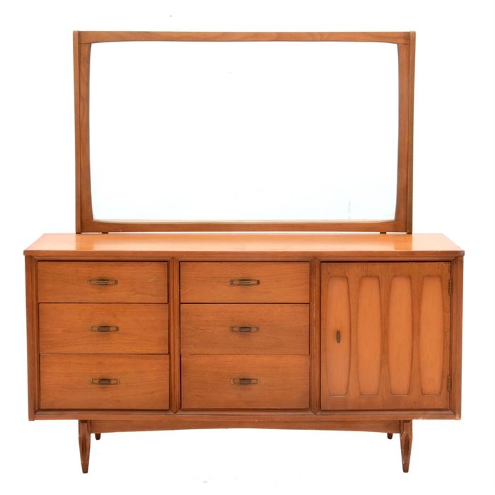 Mid Century "Mainline" Dresser With Mirror by Hooker: A mid century Hooker Mainline dresser with mirror in light walnut finish. The dresser case features a rectangular top with six exterior drawers and a single door, opening to three interior drawers, and standing on a tapered leg base. Marked to inside drawer with maker’s burn mark.
