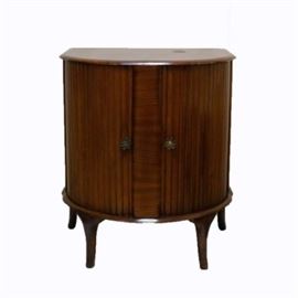 Stor-a-Wile Bar Cabinet: A Stor-A-Wile bar cabinet. This cabinet, by George Serlin & Sons LTD, is an art deco style piece. It has tambour cabinet doors that open to reveal one top shelf with a gallery and a lower storage cabinet. It dates to the 1930s-1940s.