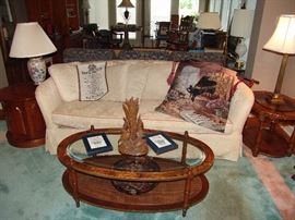 Upholstered tuxedo style sofa and oval glass top and wicker bottom cocktail table