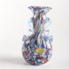 Murano Multicolored Glass Vase: A Murano multicolored glass vase. This small handblown glass vase features a swirling visual in mostly primary colors with two applied ribbon handles. The islands of Murano are famous for glassworks and this piece has retained its sticker identifying it as from Vetreria Artistico Cavagnis Maria Made in Murano.