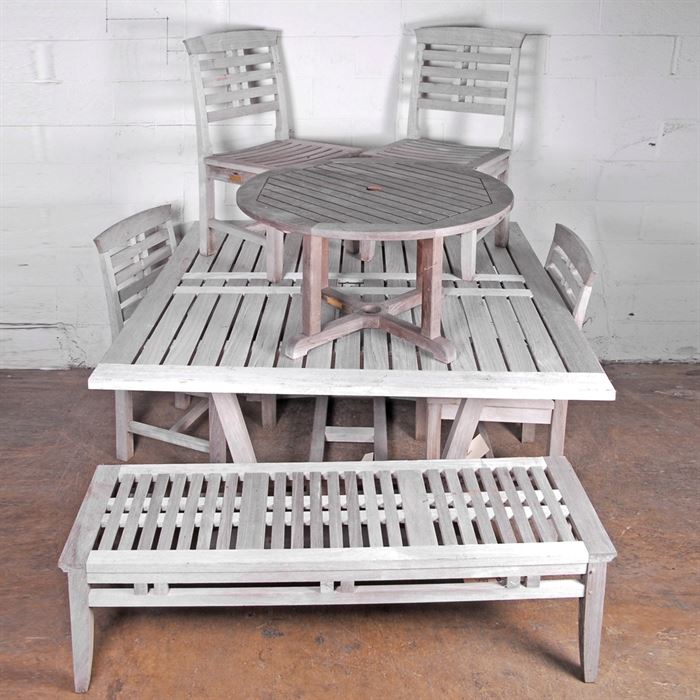 Teak Patio Set: A teak patio set. This set comprises a large dining table, bench, four chairs, and a side table with holes for an umbrella. the set is made for Kingsley-Bate out of Manassas Virginia.