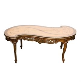 Serpentine Table With Floral Motif Inlaid Wood Top: A serpentine table with a floral motif inlaid wood top. The apron on each side of the table features an ornate carving of lattice covered with flowers surrounding an angel The four cabriole style legs are embellished with carved detail of acanthus. A fitted piece of glass protects the top.