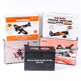 Harley-Davidson Die-Cast Replica Airplane Banks: A collection of Harley-Davidson die-cast replica airplane banks. Included are five coin banks in their original boxes. There are a “1:6 Scale Bi-Wing Pedal Plane”; a "1:32 Scale 1929 Travel Air Model “R” Mystery Ship"; and a "Lockheed F-16 “Fighting Falcon” Jet". Also included are a “Lockheed Vega 5B Highwing” and a “1:32 Scale Vintage Airplane Bank, stock number 0820”.