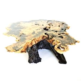 Epoxied Buckeye Burl Coffee Table by Wheeler: An epoxied buckeye burl wood coffee table by Wheeler. This table features a buckeye burl wood asymmetrical top above a cedar base. The table has an epoxy resin finish. The underside is marked with the table’s components: “Buckeye Burl Table W/ Western Red Cedar Stump Base Epoxy Resin Finish.” The maker’s mark reads “By Wheeler,” and includes the company’s phone number. For matching pieces, see items 17DET022-007 and 17DET022-082.