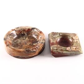 Large Agate Ash Receivers: A pair of large agate ashtrays. Includes one ash receiver in a round design, and another of a squared design. The square ashtray has an attached sticker marked “Made in Pakistan.”