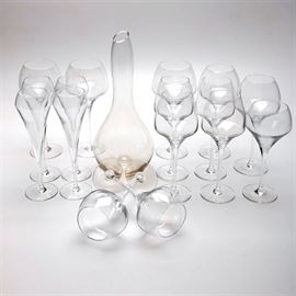 Collection of Sixteen Mikasa Wine Glasses and One Decanter: A collection of Mikasa wine glasses and a decanter. The group includes four champagne glasses, four white wine glasses, and eight red wine glasses. Each glass has a long slender stem and wide angular bowl. They are marked “Mikasa”. The decanter has a long slender neck and bulbous body.