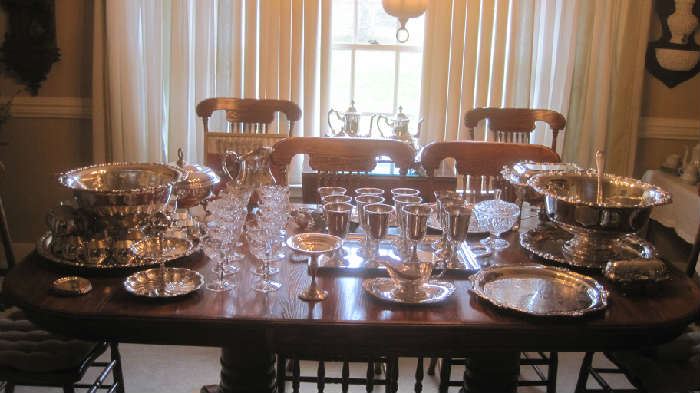 Dining table with 12 sterling goblets, silver plate hollowware: inc. 2 punch bowls with tray/ladle (one on left has liner in bowl and on tray and 24 cups)  