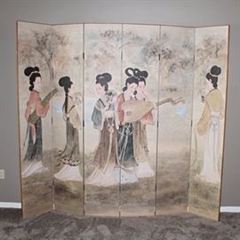 Chinese Inspired Folding Screen: A Chinese inspired folding screen. The six-panel screen, constructed from cloth on wood, depicts a group of women playing different musical instruments against a backdrop of trees and cranes taking flight.