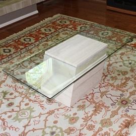 Contemporary Marble Table: A contemporary marble and glass coffee table. The table features a rectangular, beveled glass top positioned between two pieces of sand colored stone in the shape of a parallelogram.