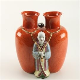 The Haldon Group Asian Inspired Double Vase: A Haldon Group Asian inspired double vase. This ceramic orange/brown double vase features two figures in Asian garb to the front and back of the piece. Each figure hold gold tone rope that circles the base of the vases’s neck. It is marked “The Haldon Group” to its underside.