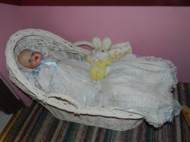 Porcelain baby doll with vintage christening gown and hat in basket