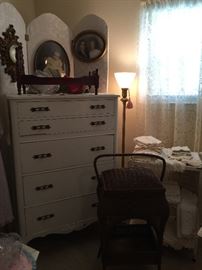 A close look at the 5 drawer chest, a doll be with bedding, wicker doll chair, floor lamp