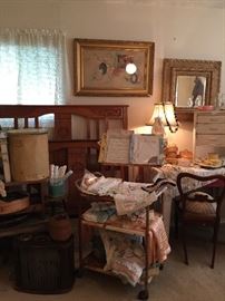 A rusty three tier metal cart with handles, vintage baby linens and clothes, metal music stand, vintage music, wonderful gold framed photos with a hand painted mat. Antique full bed, great carved detail with rails.