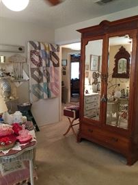 The antique wardrobe matches the full bed it has beveled glass in the doors, a great detailed crown. Quilts and other painted pieces, vintage luggage and luggage holder.