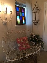 Iron settee, wall sconce, colorful window, metal cage