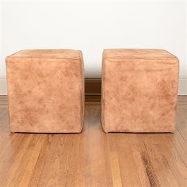 Pair of Cube Ottomans: A pair of cube ottomans. Each ottoman features a squared top, panel sides and rests on pad feet. The ottomans are upholstered in a camel tone micro-suede and have piping accents at the top edge.