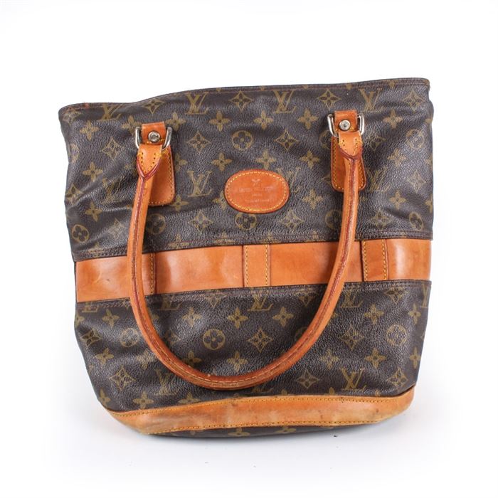 Vintage Louis Vuitton handbag: A vintage Louis Vuitton handbag. This dual-handled tote showcases the signature Louis Vuitton monogrammed coated canvas exterior, and is accented with tan leather handles and a matching leather band along the exterior. The interior features a leather label stamped “Louis Vuitton Paris".