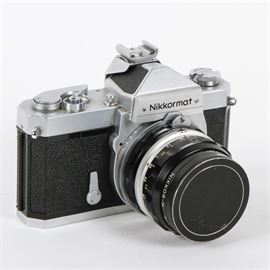 Vintage Nikon Nikkormat FT 35mm Camera: A vintage Nikon Nikkormat FT 35mm camera. This camera features a Nikkor-H Nikon lens, and a model number of FT 3877295 on the top. This camera comes with a black leather Nikon carrying case and a shoulder strap attached to the camera. The camera and case are both marked Nikon in various places.