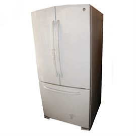 Contemporary GE Refrigerator: A contemporary GE refrigerator. This appliance with a two-door refrigerator section in the top features the freezer section below. This section has a drawer that pulls straight out. The doors have three compartments each and the main body features two shelves with three clear drawers. The refrigerator and the freezer temperatures can be adjusted. A label affixed to the appliance reads “General Electric Company – Appliance Park – Louisville, KY – Made In Mexico” and “Model No. GFSF2KEXA WW”.