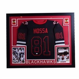 Framed Autographed Jersey of Blackhawks Marian Hossa: A frame hockey jersey. This piece is a replica of the jersey worn by Martin Hossa and features a pair of images of him and his team winning the Stanley Cup and has his signature present horizontally on the number 8 of the jersey. The Jersey is held in a matte black wooden frame with a COA from the JSA present on the verso below the wire hanger.