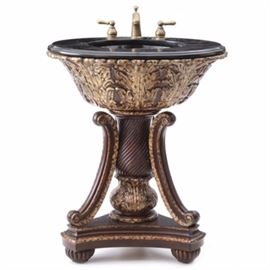 Ornately Molded Pedestal Sink: An ornately molded bathroom pedestal sink. The sink features a tessellated black stone top with molded edge, having a black ceramic basin and a brushed bronze tone metal faucet. The composite pedestal has deeply molded acanthus leaves supporting the sink basin, on bulbous molded pedestal with scrolled bracket supports, on molded bun feet. Unmarked.